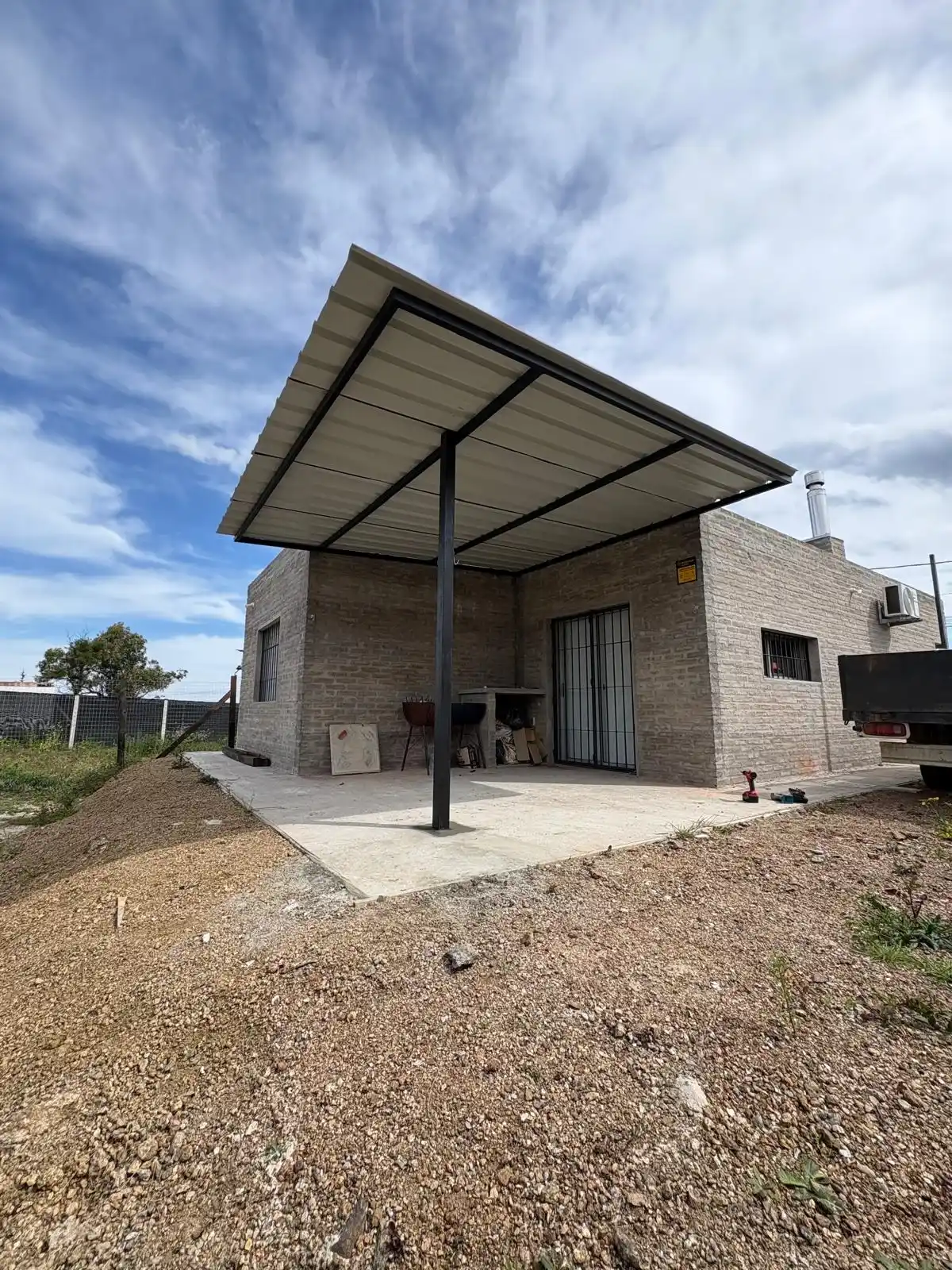 Pérgola metálica terminada en casa de ladrillo